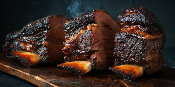 A large steaming fragrant piece of baked beef brisket on the ribs with a dark crust. Classic Texas barbecue