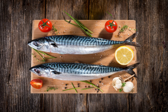 Fresh mackerel on wooden board served with lemon and herbs