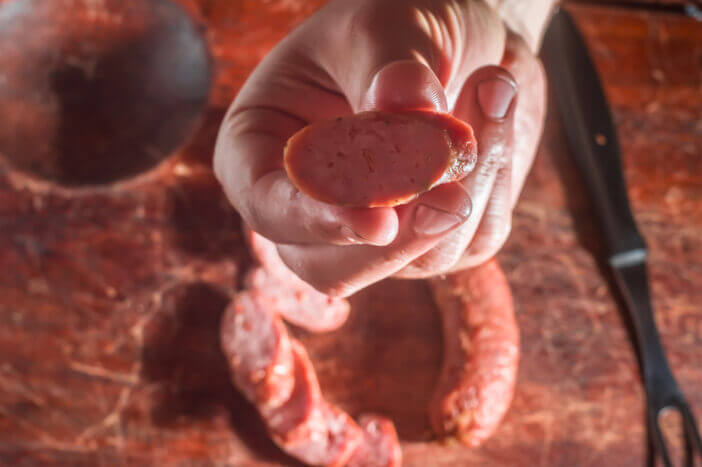 Sliced smoked calabrese sausage in a wooden table,copy space.