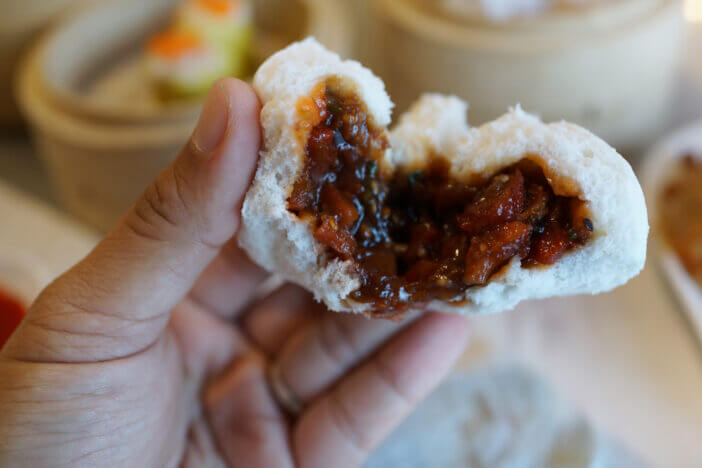 Close up hand holding a steamed pork bun - Cha Siu Bao