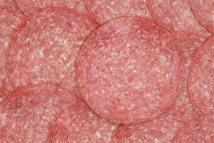 Genoa sliced salami background with top view