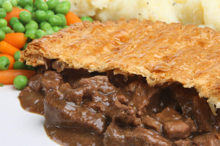 Steak pie with mashed potato, peas and carrots.