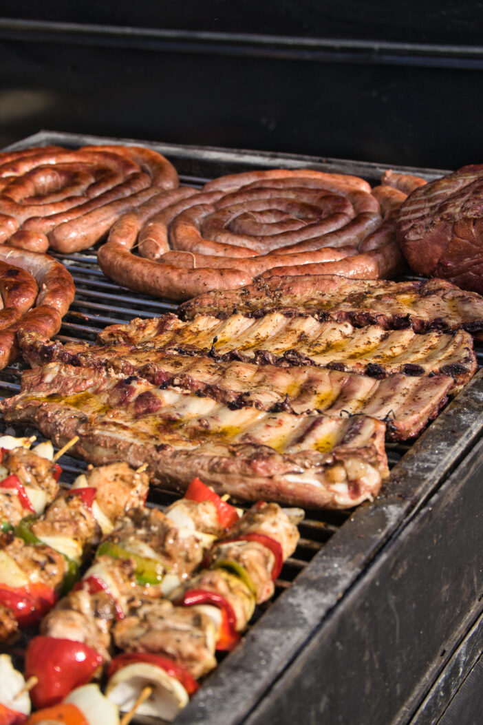 Argentine barbecue, cook preparing grilled meat. Sunny day. Festivity, celebration, banquet.