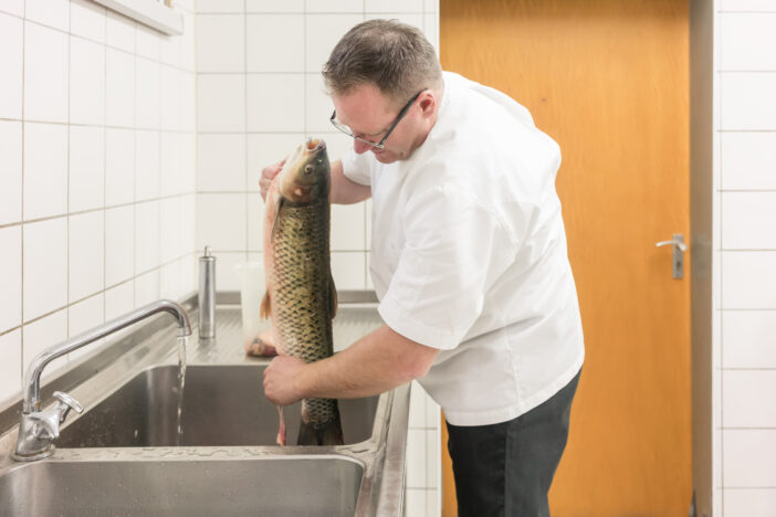 5+ Reasons Why Saltwater Carp are the Perfect Catch 3 Chef gutting carp fish to prepare it later