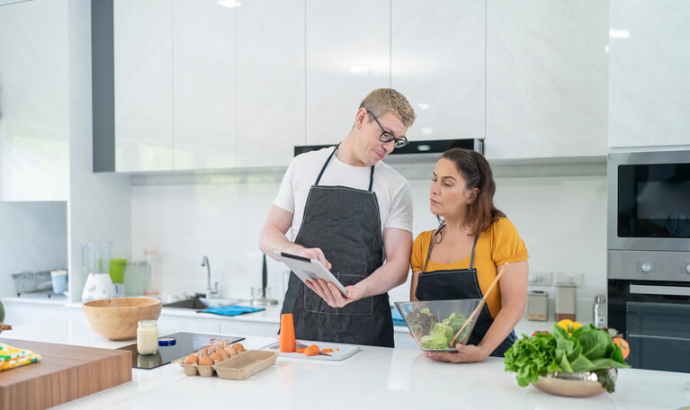 A couple learns to cook in their own kitchen.