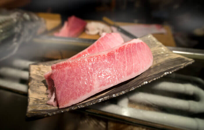 5+ Reasons Why Otoro Tuna is the Best Sushi Treat 1 cutting of otoro from blue fin tuna for sashimi at the kitchen bar of sushi restaurant photo with indoor very low and dark lighting.