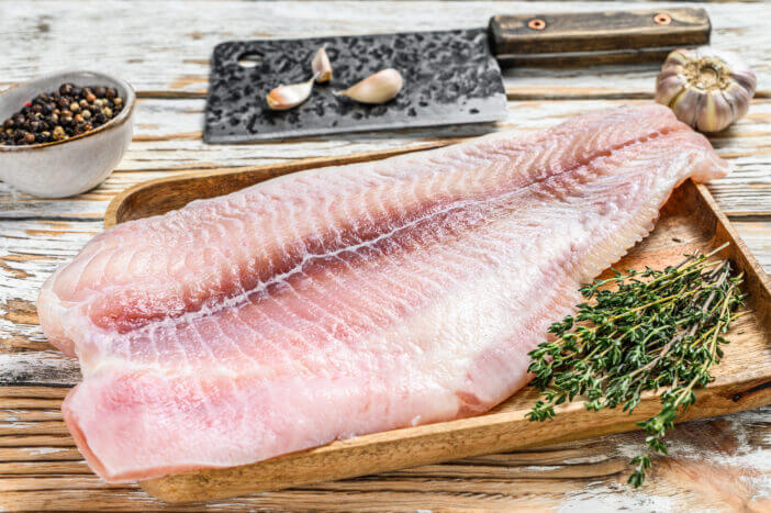 Fresh raw white fish fillet catfish with spices. White wooden background. Top view.
