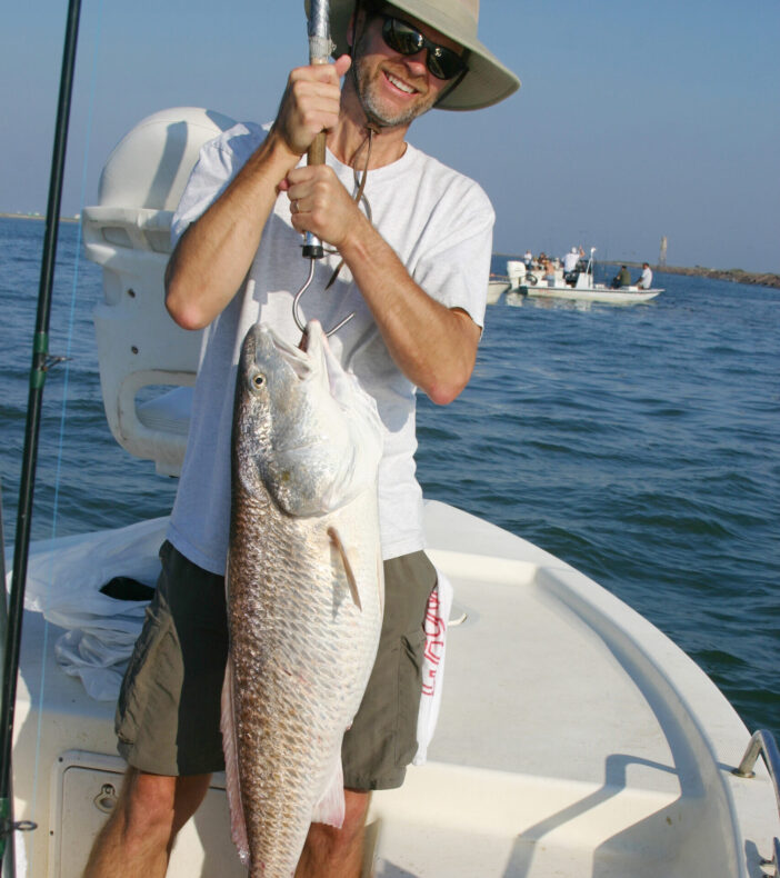 Happy fishermans holds up big redfish