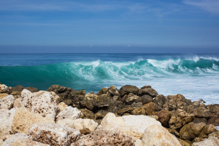 sea view. blue ocean, big waves, black and white stones, high tide