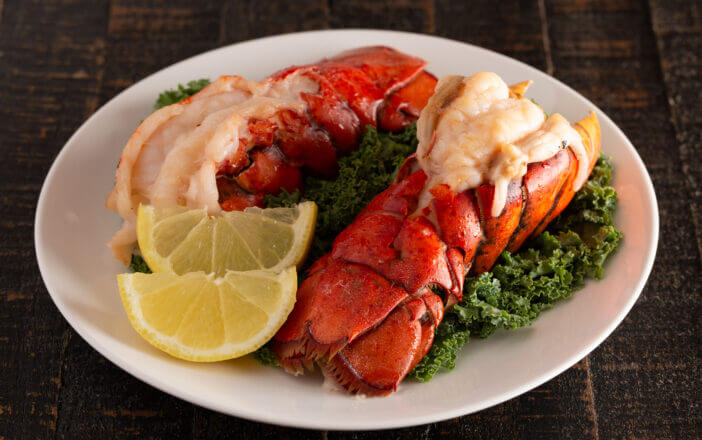 10+ Things You Need to Know About What Lobster Tastes Like 2 Two Broiled Lobster Tails on a Bed of Kale with Lemon Slices