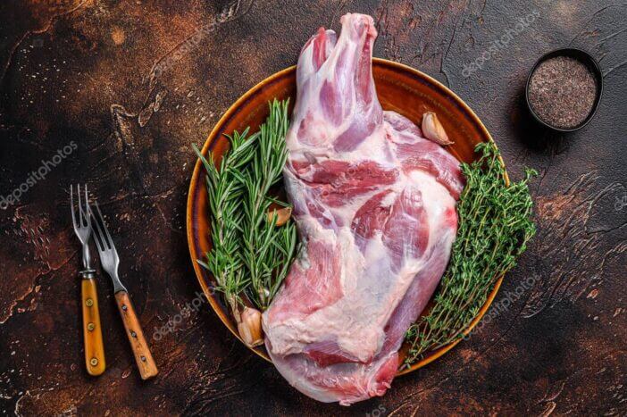 12+ Best Things to Smoke for Beginners 3 Whole fresh Raw lamb shoulder meat on a plate. Dark wooden background. Top view.