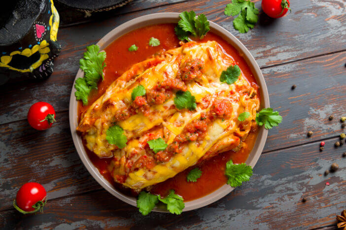 10+ Tasty Mexican Meats That Will Spice Up Your Meal 6 Enchilada with beef with tomato sauce on wooden table, mexican kitchen top view