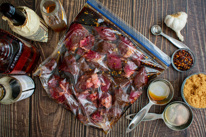 Walkerswood Traditional Jerk Marinade: Our Review To Spice Up Your Meals 1 Uncooked beef tips in a plastic bag surrounded by marinade ingredients