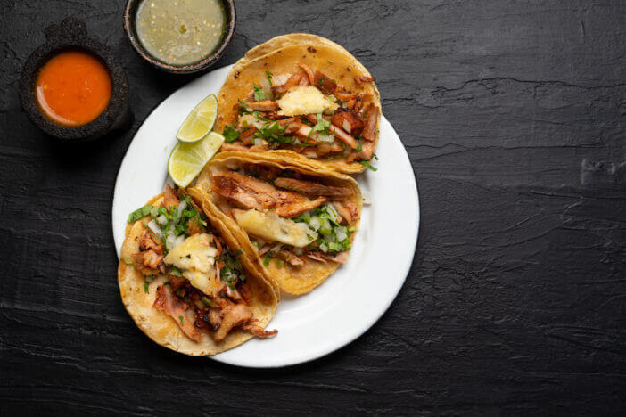 10+ Tasty Mexican Meats That Will Spice Up Your Meal 4 Pork tacos called al pastor with pineapple on dark background. Traditional mexican tacos