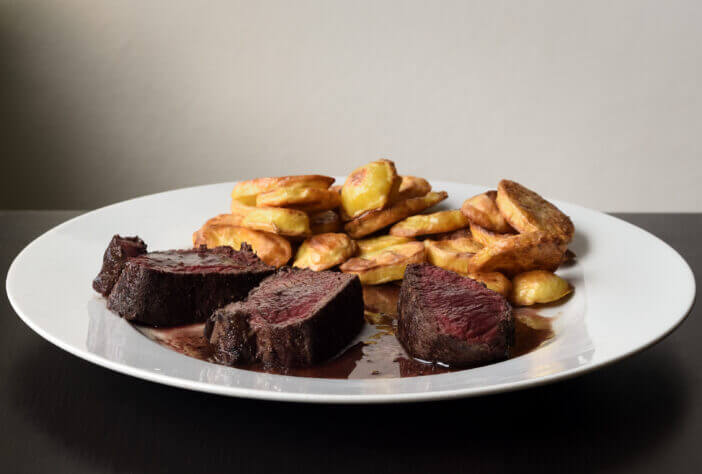 3+ Ways to Cook the Perfect Deer Backstrap Every Time 2 Deer backstrap with baked potatoes on white plate