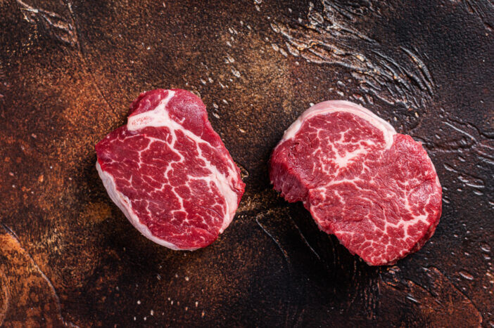 Filet Mignon vs New York Strip: Breaking Down the Debate 2 Raw Fillet Mignon tenderloin steaks. Dark background. Top view.