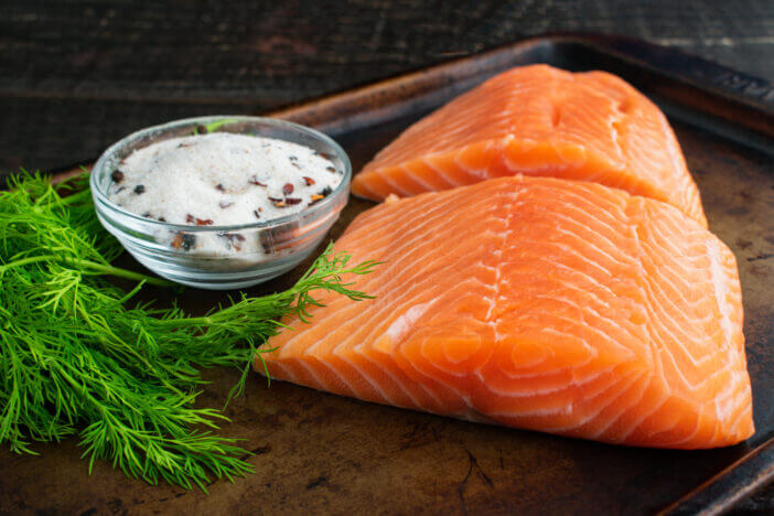 Ingredients to make lox or salt cured salmon on a metal baking sheet