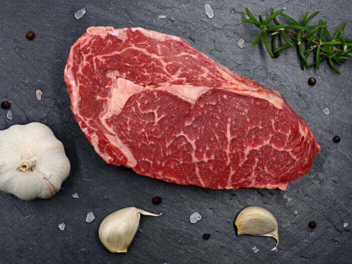 Ribeye vs Tenderloin: The Ultimate Comparison of Steak Cuts 2 marbled raw meat Steak Ribeye on black slate plate, top view of fresh barbecue beef with spices.