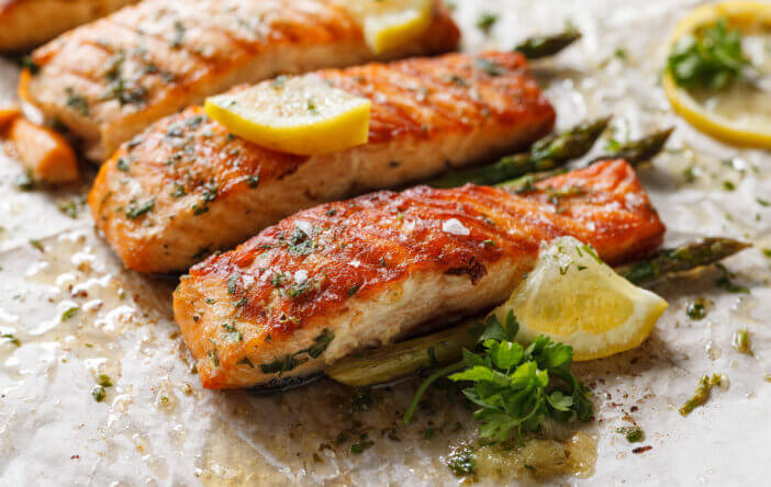 7+ Surprising Differences Between Atlantic and Alaskan Salmon 4 Baked salmon fillet with aromatic herbs and lemon on baking paper close up view