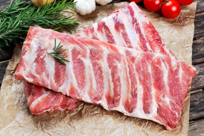 Raw ribs with a rosemary and vegetables. on crumpled paper.