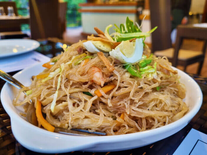 Classic pancit bihon topped with sliced hard boiled eggs, filipino, noodles, philippines, popular, classic, carrots, carrot, philippine, savory, toppings, healthy, chicken, cabbage, authentic, bihon, boiled, egg, sliced, yellow, yummy, healthy eating