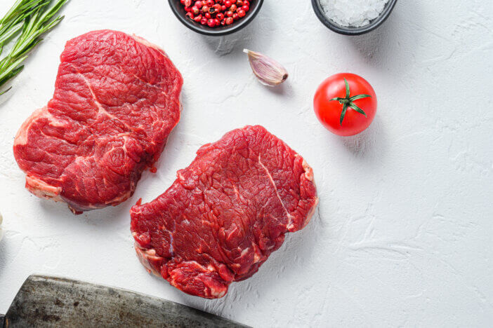 11 Low Fat Meat Options For Health & Fitness Enthusiasts 8 Raw rumpsteak, farm beef meat with seasonings, rosemary, garlic and butcher cleaver. White textured background. Top view space for price