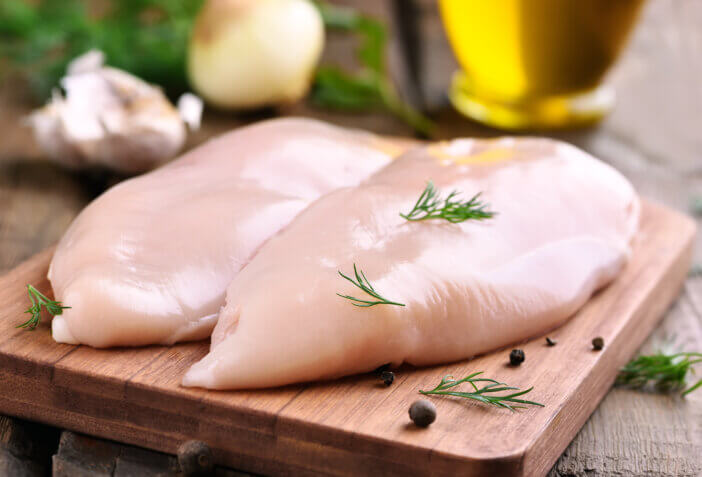11 Low Fat Meat Options For Health & Fitness Enthusiasts 2 Raw chicken breasts and spices on wooden cutting board, close up view
