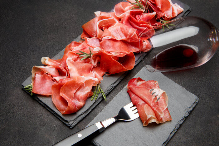 11 Gourmet Meat Gift Sets For This Holiday Season 6 Italian prosciutto crudo or spanish jamon anw glass of wine on concrete backfround background.