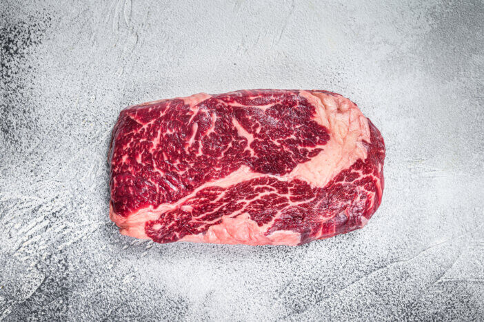 9 Gourmet Meats For Cooking For Home Chefs & Food Bloggers 7 Raw rib eye beef meat steak on a table prepared for the gril. White background. Top view.