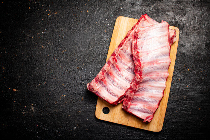 9 Lean Grass Fed Beef Cuts For Health & Fitness Enthusiasts 7 Raw ribs on a cutting board. On a black background. High quality photo