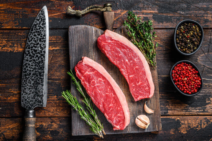 9 Lean Grass Fed Beef Cuts For Health & Fitness Enthusiasts 5 Raw top sirloin beef meat steak on a cutting wooden board. Dark wooden background. Top view.