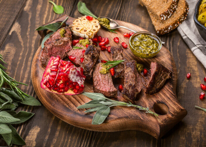 7 Uses for Exotic Meat Cuts For Foodies & Culinary Adventurers 2 Kangaroo meat steak with green pesto and pomegranate on wooden cutting board. Helthy holiday food concept. Selective focus.