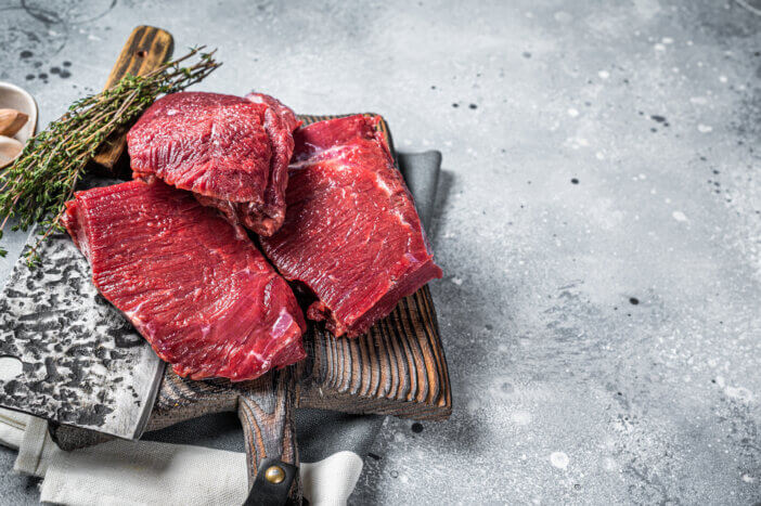 11 Gourmet Meat Gift Sets For This Holiday Season 11 Raw Venison dear meat on butcher cutting board, game meat. Gray background. Top view. Copy space.